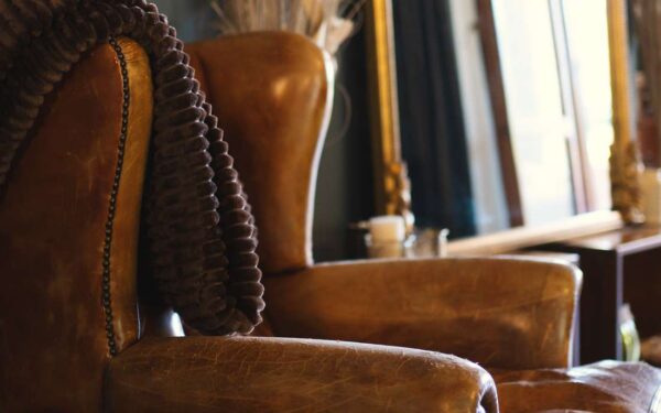 Leather armchair and gilded mirror in the warm interior of Villa Elena