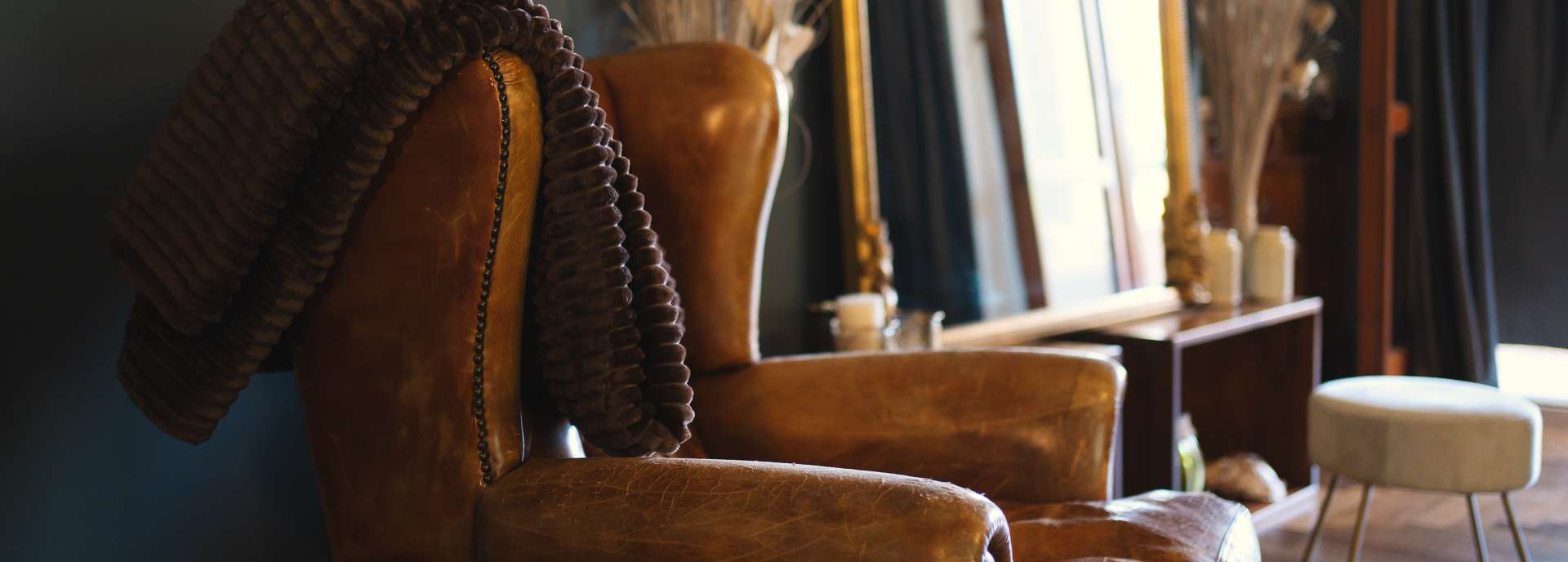 Leather armchair and gilded mirror in the warm interior of Villa Elena